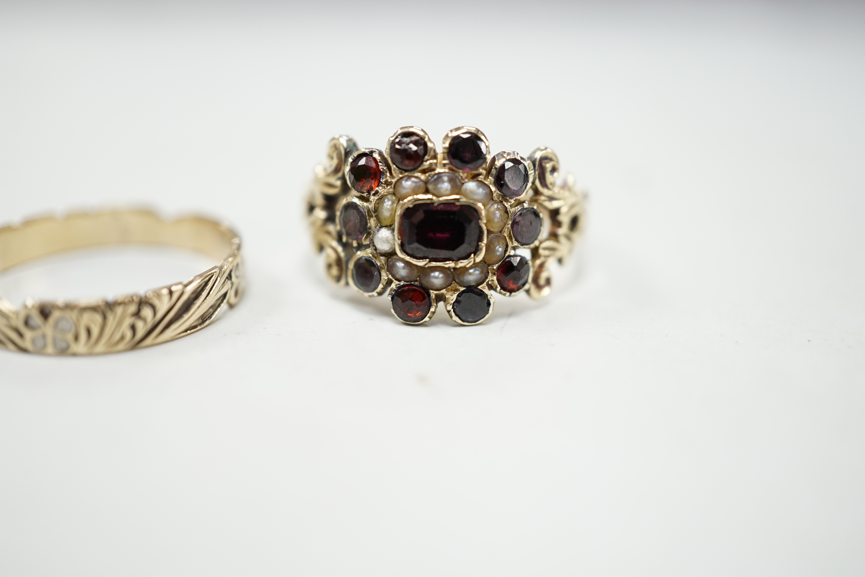 An early 19th century yellow metal, garnet and seed pearl cluster set ring, size P and a 19th century yellow metal and two colour enamel set band.